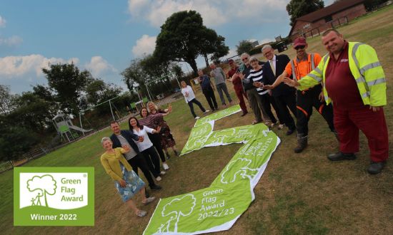 A group of volunteers stood around five green flags in the park